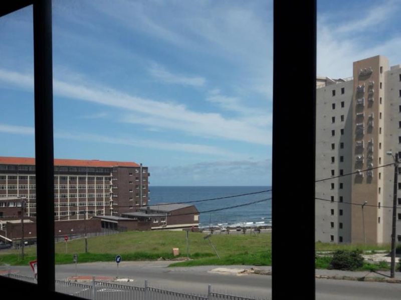 A view of the ocean and surrounding urban buildings captured from inside the apartment.