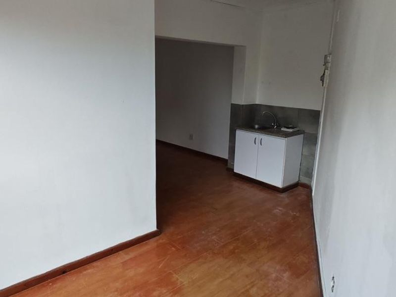 A compact, empty kitchen area featuring basic base cabinetry, a sink, and a tiled backsplash, ready for renovation or customization.