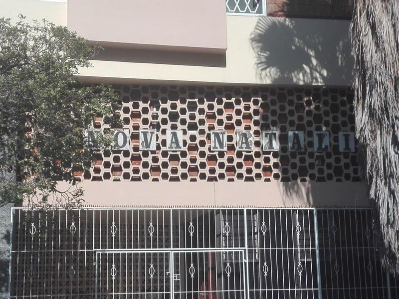 Front facade of the Nova Natali apartment building featuring a distinctive honeycomb breeze block screen and secure metal entrance gate.