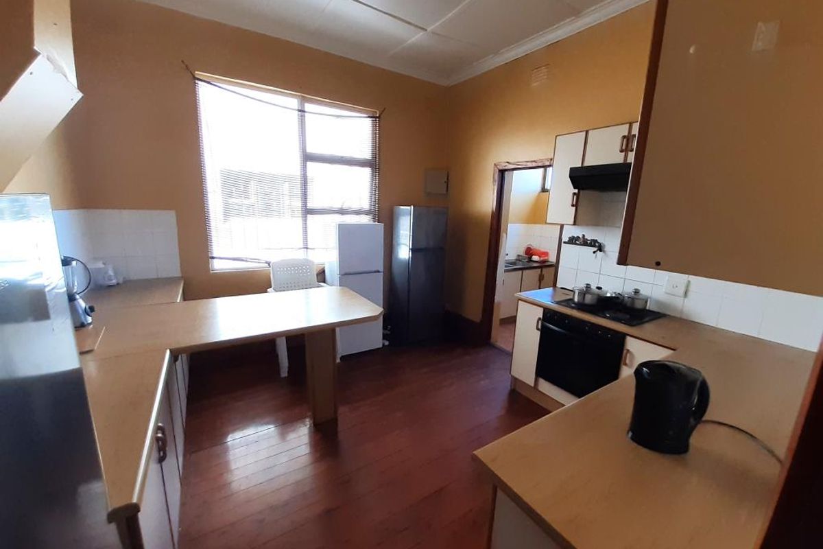 A dated kitchen featuring timber flooring, laminate countertops, and built-in cooking appliances, offering significant potential for modernization and renovation.
