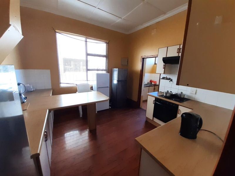 A dated kitchen featuring timber flooring, laminate countertops, and built-in cooking appliances, offering significant potential for modernization and renovation.