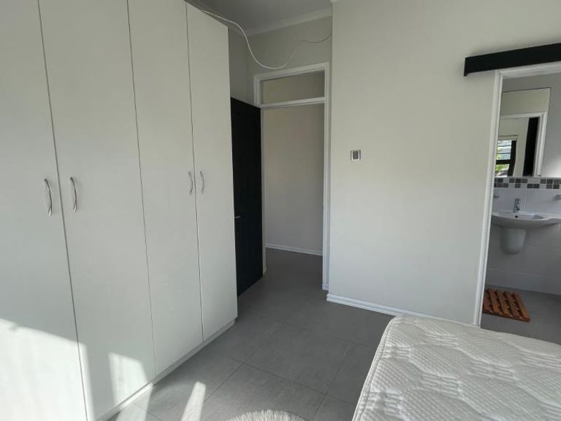 A bedroom featuring built-in cupboards, tiled flooring, and direct access to an en-suite bathroom through a sliding door.