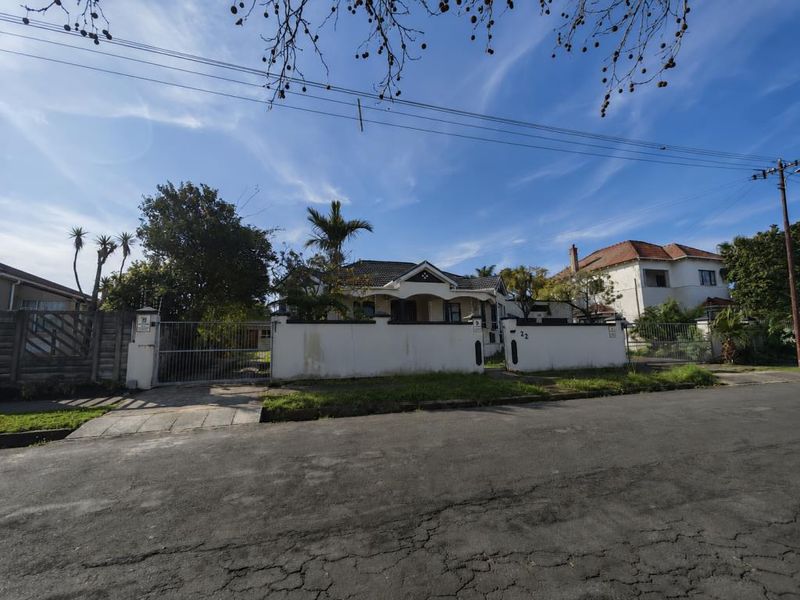 Front elevation of a residential property featuring a tiled roof, perimeter wall, and gated driveway access from the street.