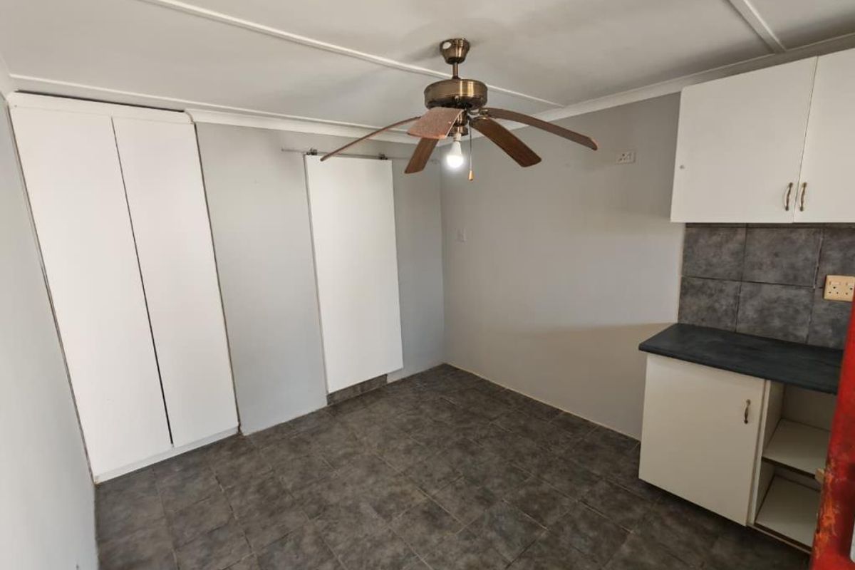 A functional kitchen area featuring tiled flooring, built-in cabinetry, a tiled backsplash, and a ceiling fan.