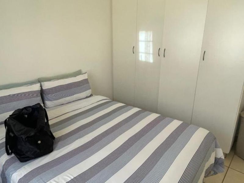 A functional bedroom featuring built-in wardrobes and tiled flooring, providing a clean and practical living space.