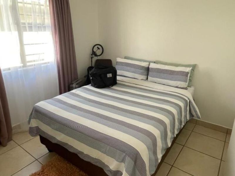 A functional bedroom featuring tiled flooring and built-in cupboards, providing essential storage space and a neutral foundation for personalization.