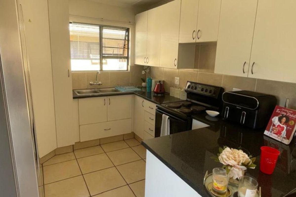 A functional kitchen featuring white cabinetry, dark granite countertops, tiled flooring, and a built-in electric stove with a tiled backsplash.