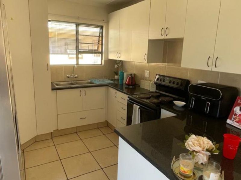 A functional kitchen featuring white cabinetry, dark granite countertops, tiled flooring, and a built-in electric stove with a tiled backsplash.