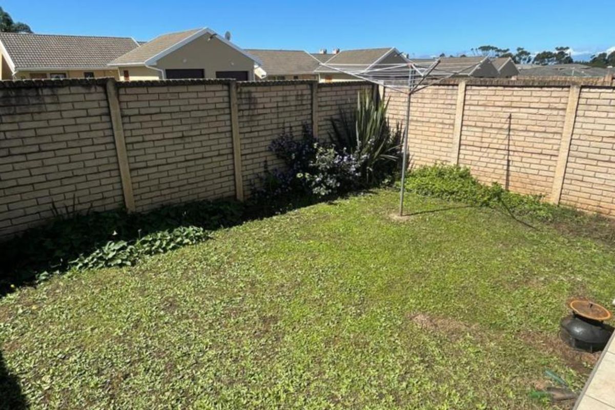 A private rear garden featuring a lawn area enclosed by brick boundary walls and a rotary clothesline.