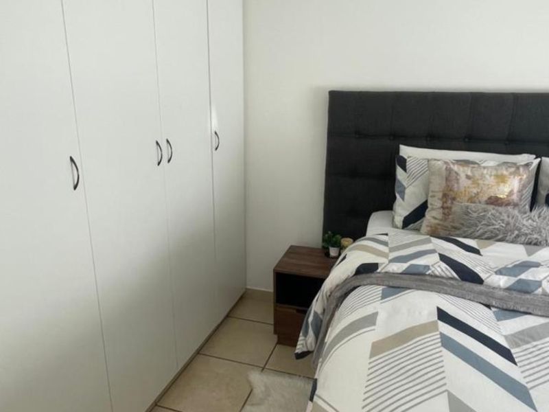 A well-maintained bedroom featuring neutral tiled flooring and ample built-in cupboard storage space.