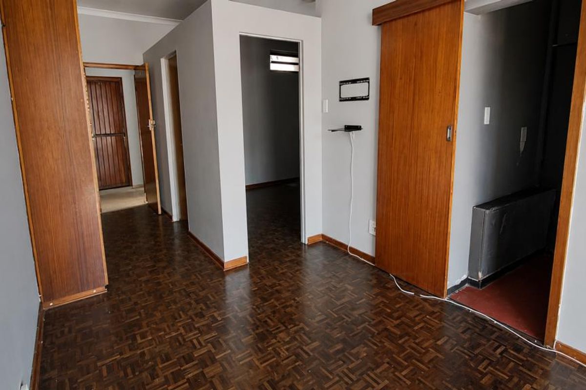 A vacant hallway featuring traditional parquet flooring, wooden door frames, and sliding doors, providing access to multiple rooms within the apartment.