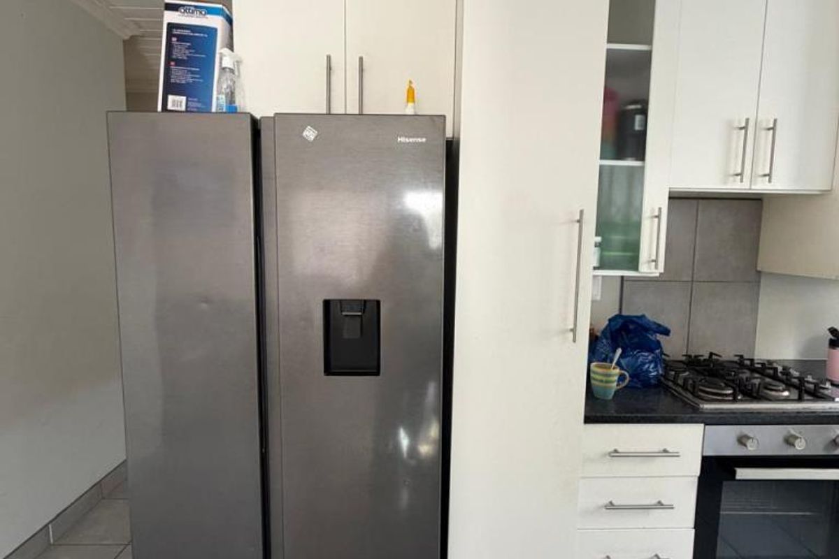 A functional kitchen area featuring white cabinetry, a gas hob, built-in oven, and tiled flooring.