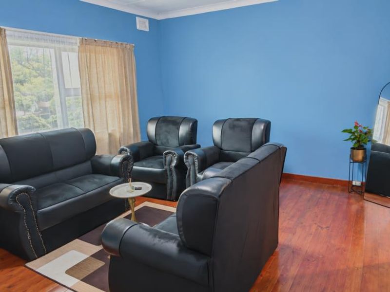 A living room featuring polished hardwood flooring, blue painted walls, and a large window with natural light.