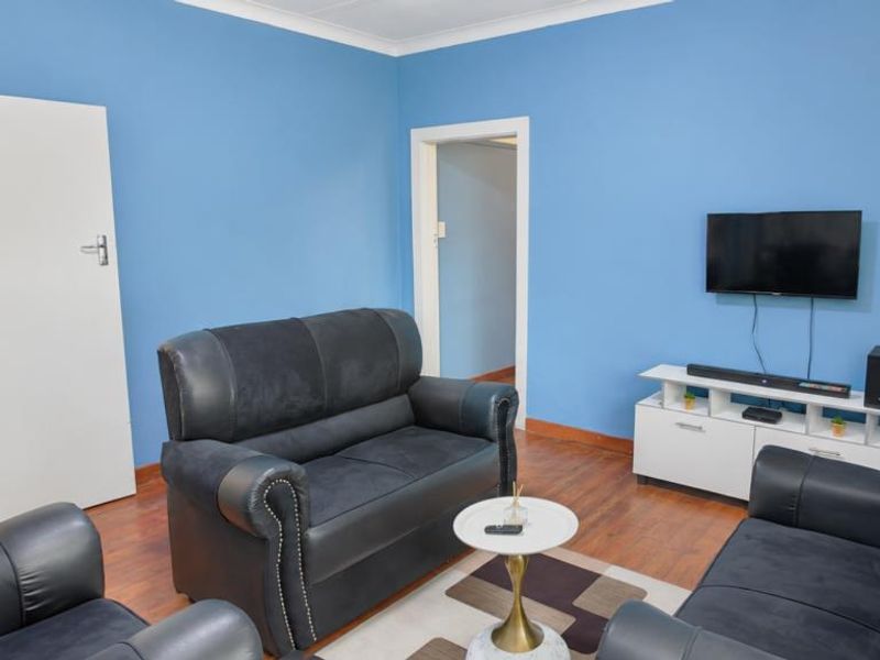 A living room featuring laminate flooring and blue painted walls, providing a functional space for relaxation.