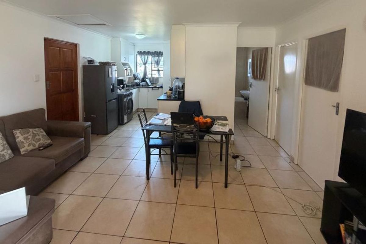 A functional kitchen featuring white cabinetry, dark countertops, a double basin sink, and tiled flooring, offering a clean and practical workspace.