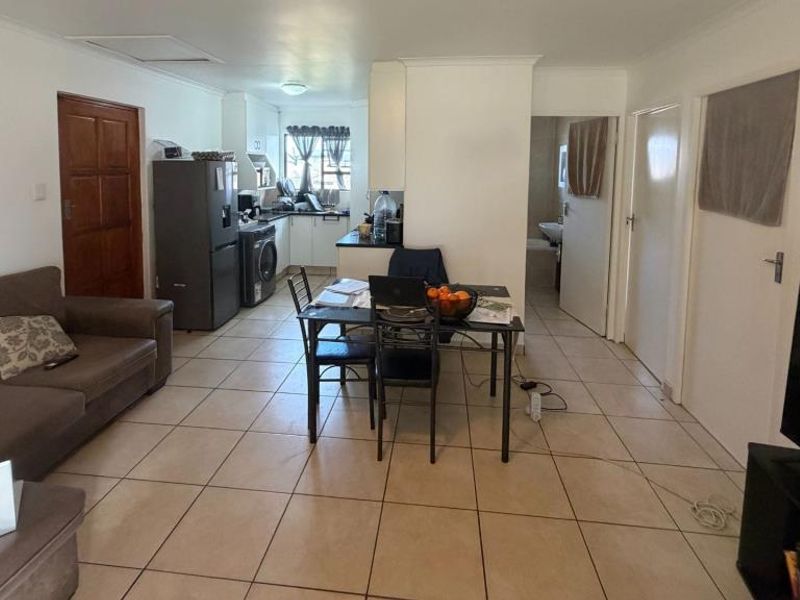A functional kitchen featuring white cabinetry, dark countertops, a double basin sink, and tiled flooring, offering a clean and practical workspace.