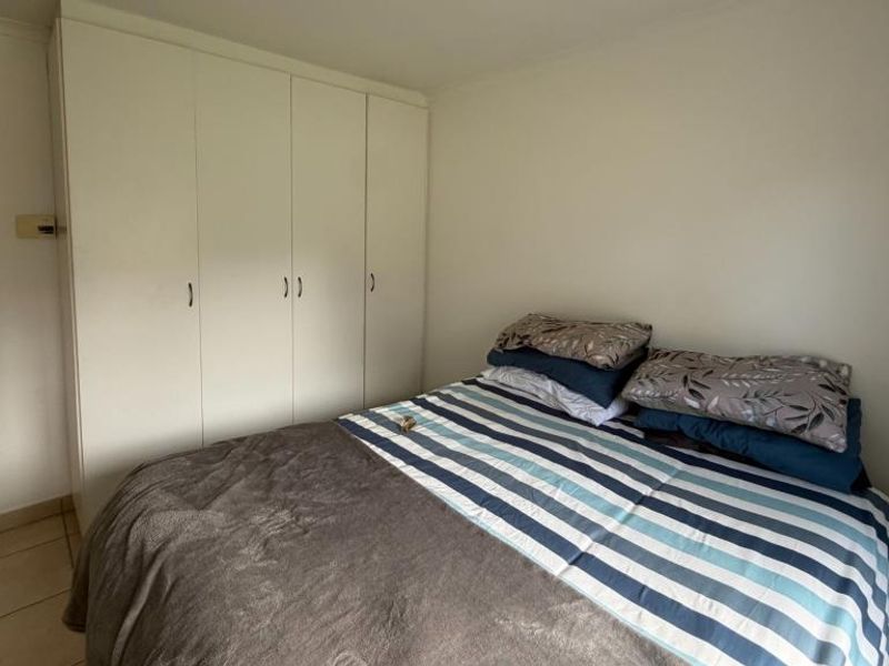 A clean, empty bedroom featuring neutral grey tiled flooring and white built-in cupboards, offering a versatile space ready for personalization.