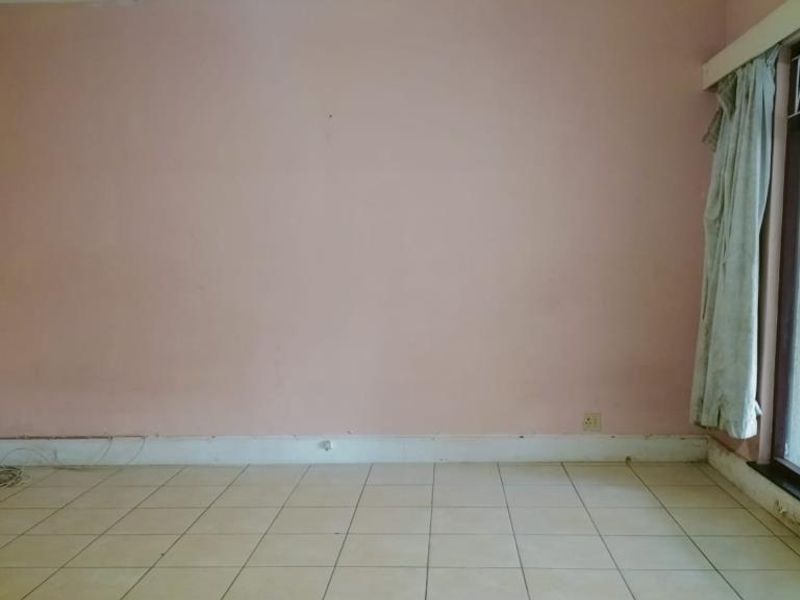 An empty living room featuring tiled flooring and a large window, requiring cosmetic updates and wall repairs to improve its overall condition.