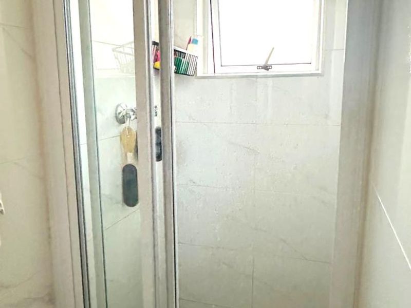 A compact shower stall featuring tiled walls, a tiled floor, and a small casement window for ventilation.