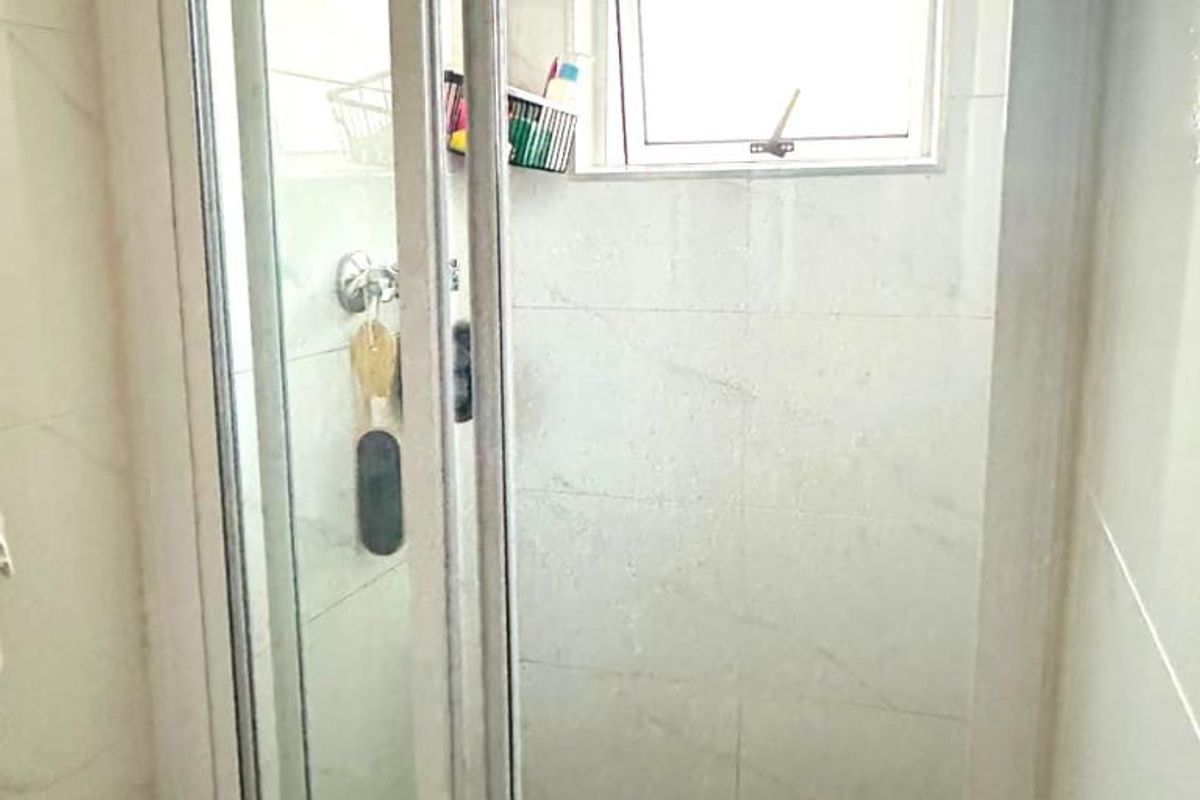 A compact shower stall featuring tiled walls, a tiled floor, and a small casement window for ventilation.