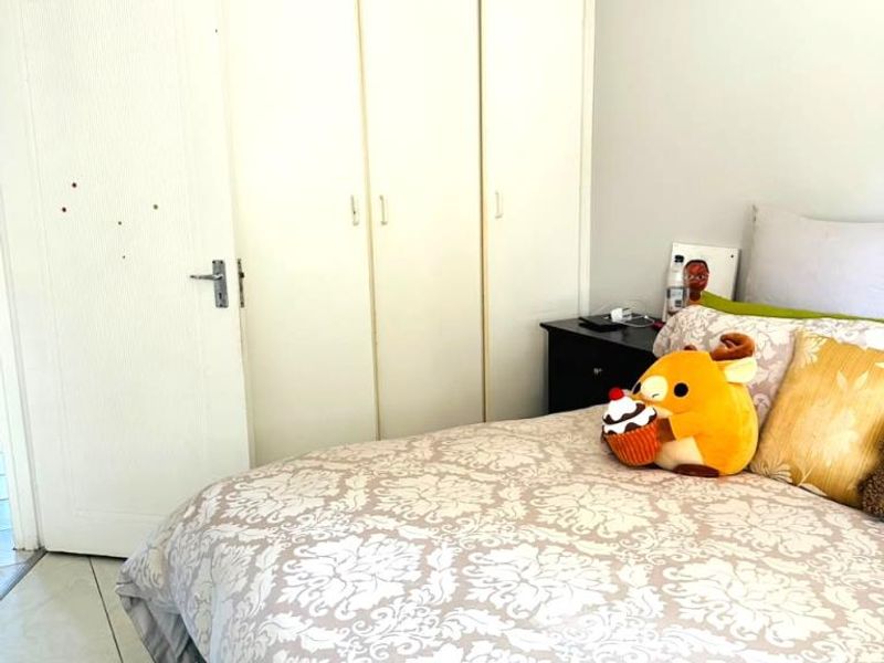 A bedroom featuring built-in cupboards, tiled flooring, and a ceiling fan. The space offers functional storage and basic finishes.