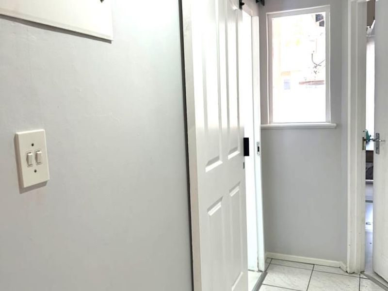 A clean, functional hallway featuring tiled flooring, a modern sliding barn door, and a wall-mounted electrical distribution board.