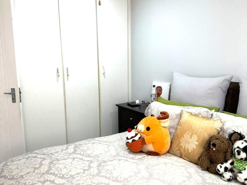 A bedroom featuring a built-in wardrobe and a ceiling fan, providing functional storage and climate control.
