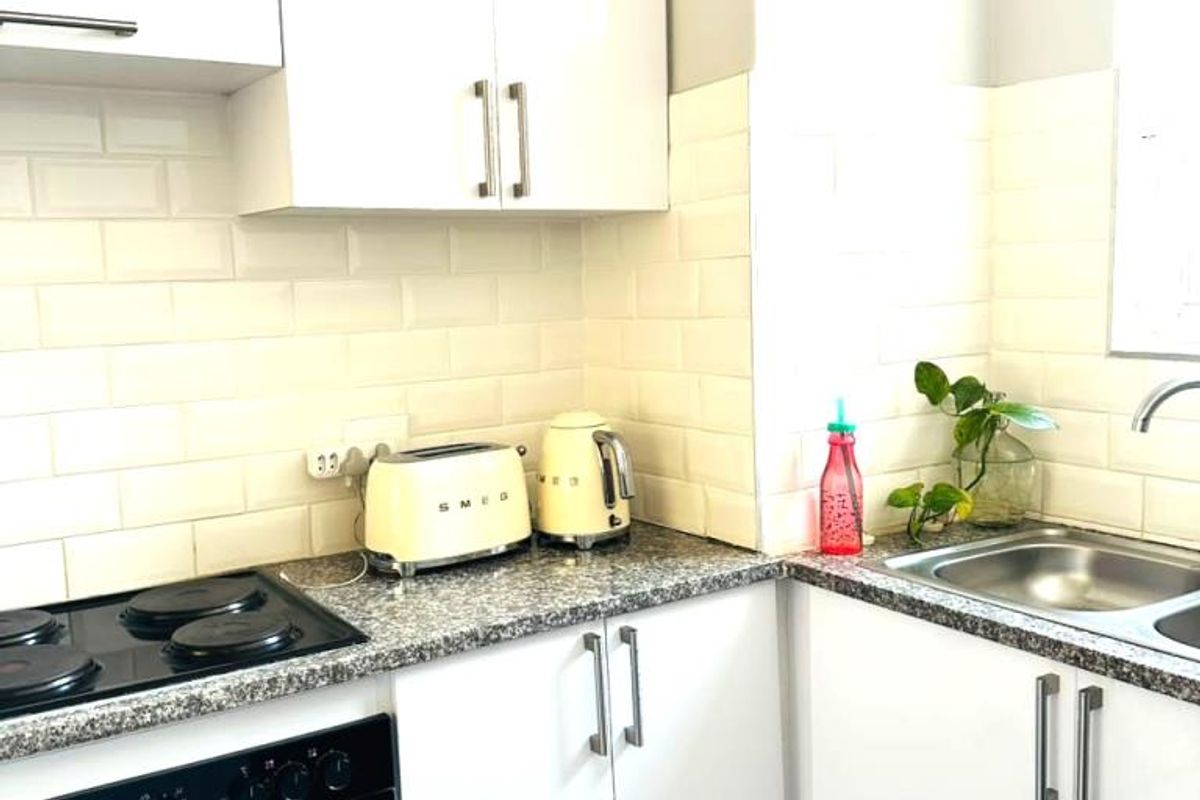 A functional kitchen featuring white cabinetry, granite countertops, a subway tile backsplash, and integrated cooking appliances.