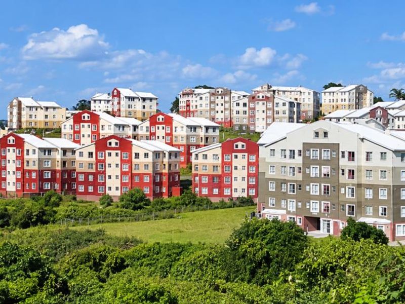 An elevated view of a residential apartment complex featuring multiple multi-story buildings with pitched roofs set within a landscaped environment.