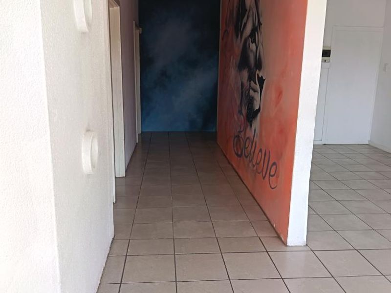 An empty hallway featuring ceramic floor tiles and a painted feature wall, providing a neutral canvas for potential commercial or office use.