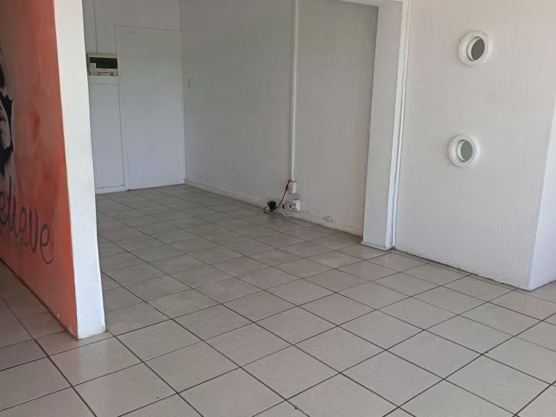 An empty open-plan commercial space featuring ceramic tiled flooring, unique porthole windows, and exposed electrical conduit, ready for custom fit-out.