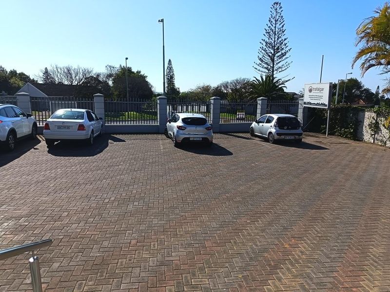 A paved commercial parking area featuring perimeter fencing, security access, and professional signage for the property.