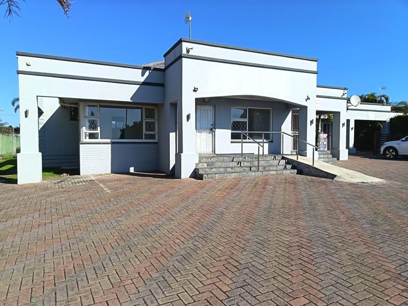 Front elevation of a commercial property featuring a paved driveway, accessible concrete ramp, and stone entrance steps with metal handrails.