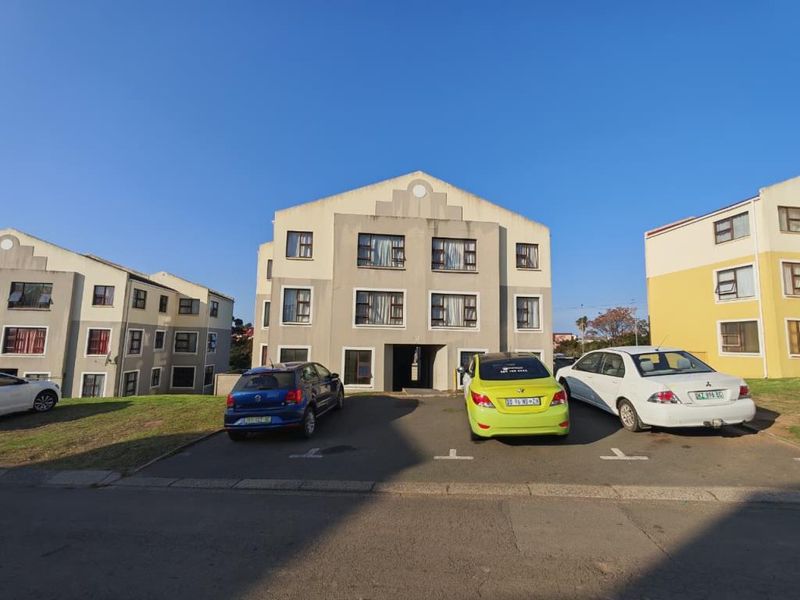 Front elevation of a multi-story apartment building featuring a paved parking area and standard casement windows.