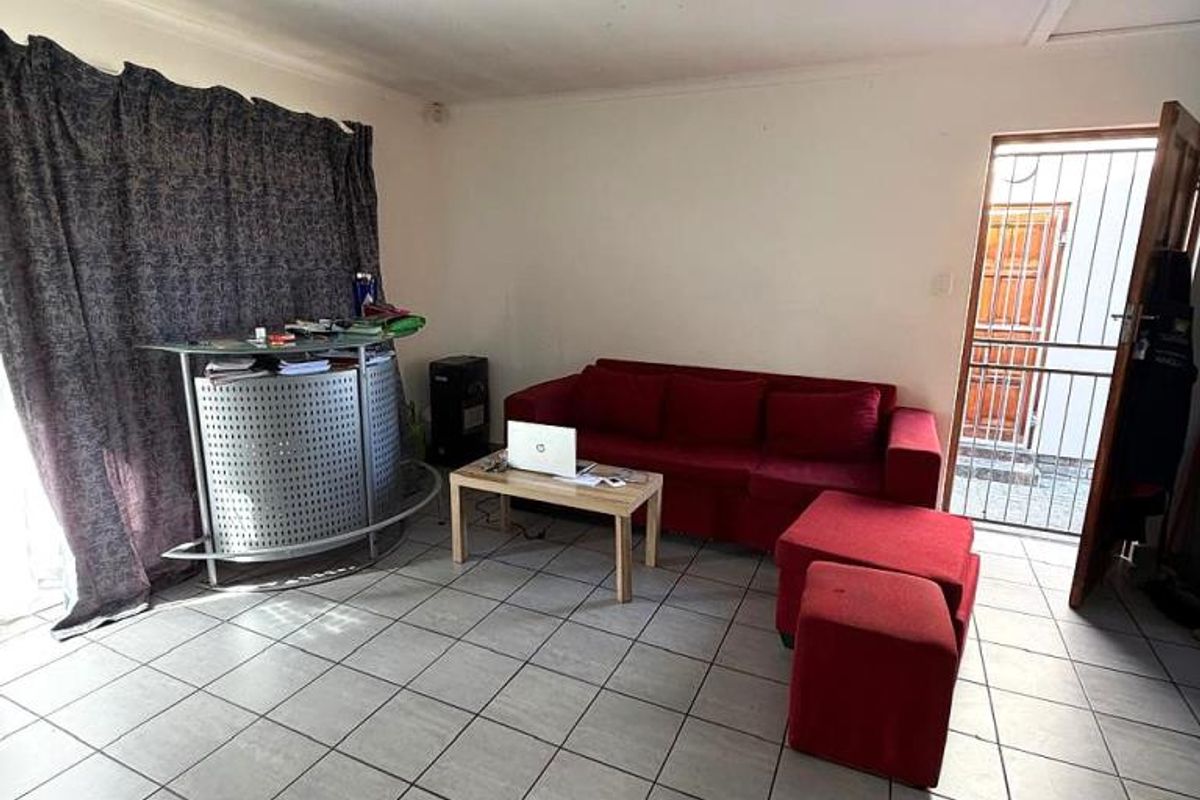 A tiled living room area featuring a security gate at the entrance and a ceiling-mounted light fixture.