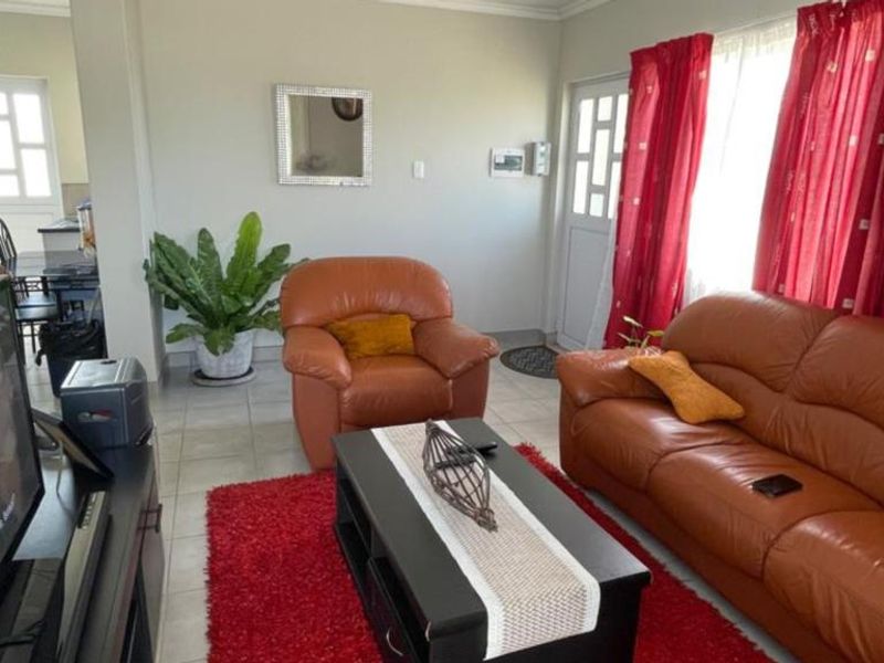 A functional living room featuring tiled flooring and direct access to the exterior via a security door.