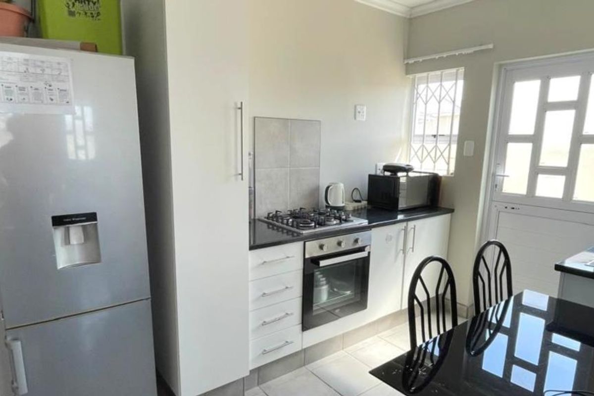 A functional kitchen featuring a gas hob, built-in oven, tiled flooring, and direct access to the exterior via a security door.