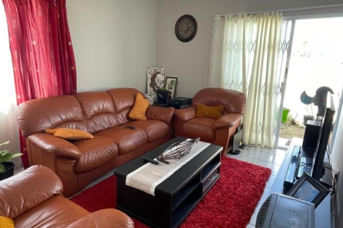 A living room featuring tiled flooring and a sliding glass door with a security gate providing access to the exterior.