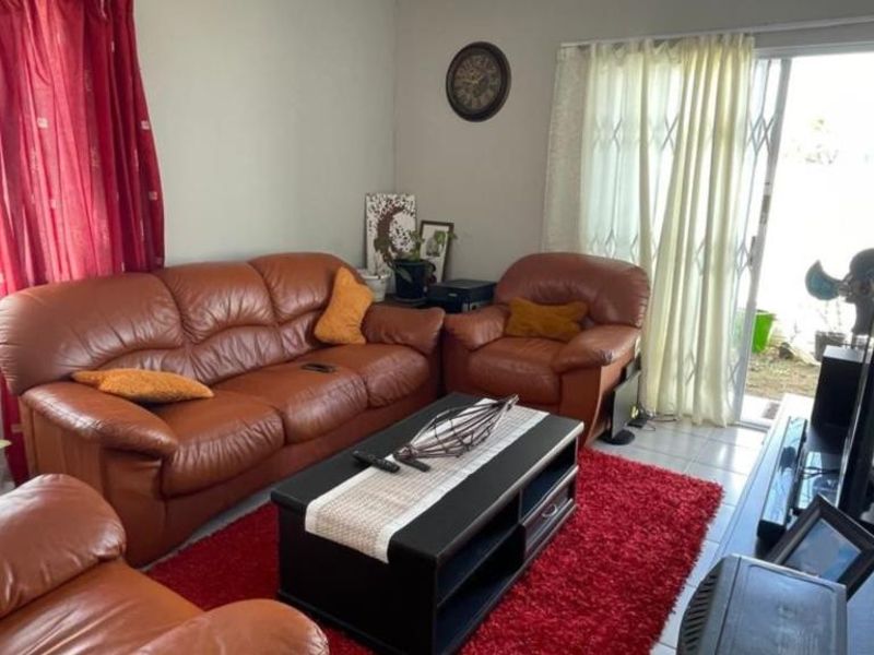 A living room featuring tiled flooring and a sliding glass door with a security gate providing access to the exterior.