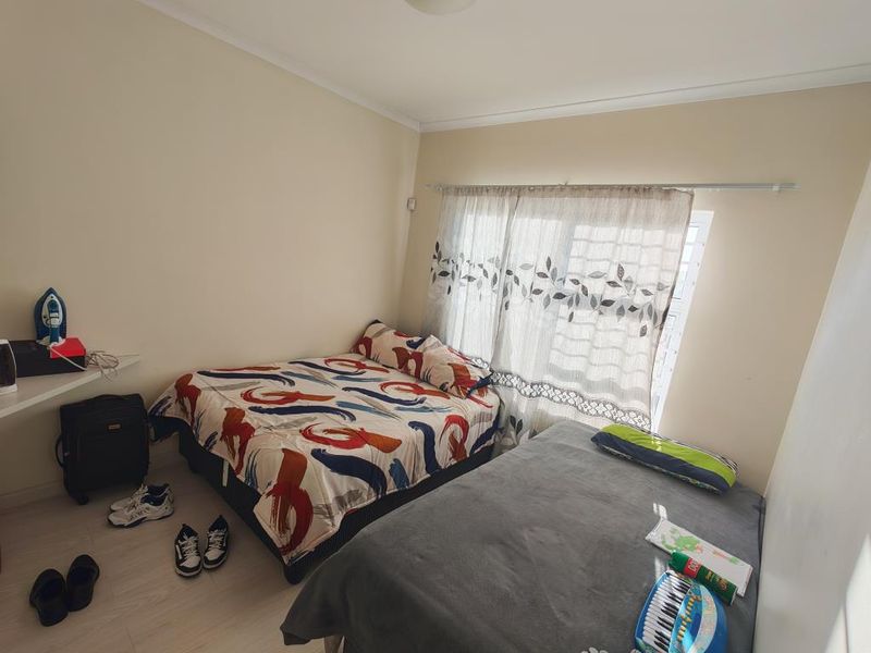 A well-maintained bedroom featuring neutral wall tones and a large, floor-to-ceiling built-in wardrobe providing ample storage space.
