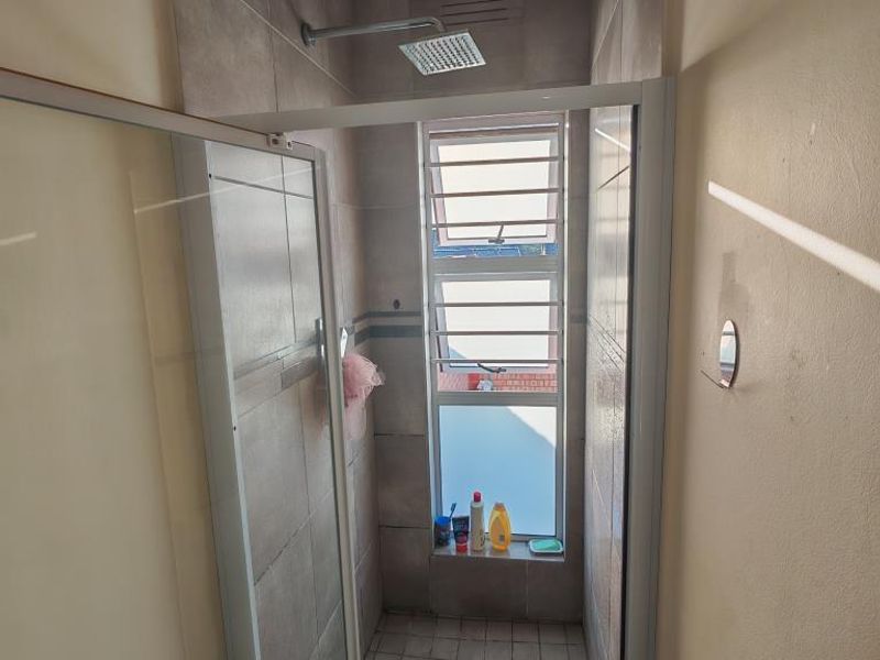 A functional bathroom featuring a built-in bathtub with tiled surround and a standard toilet, finished with neutral wall paint and tiled flooring.