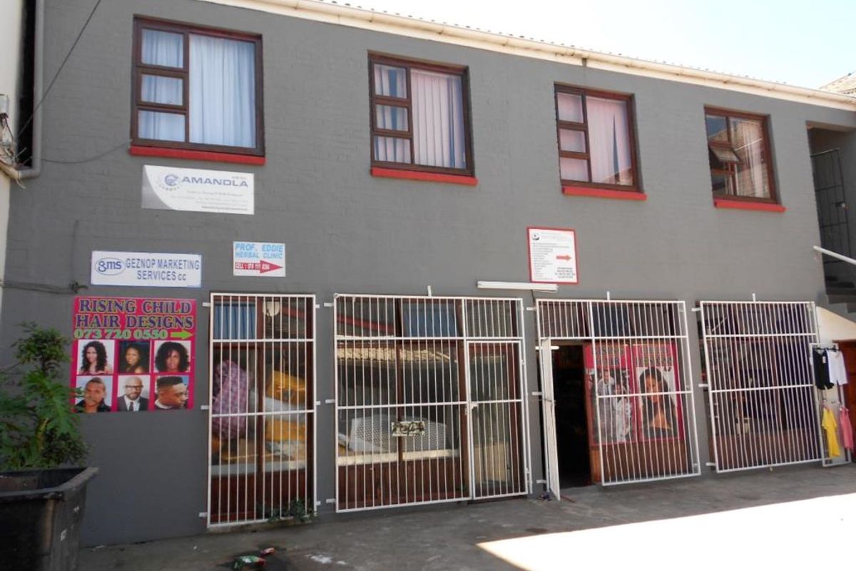 Front elevation of a commercial building featuring multiple business signage, security gates, and aluminium window frames.