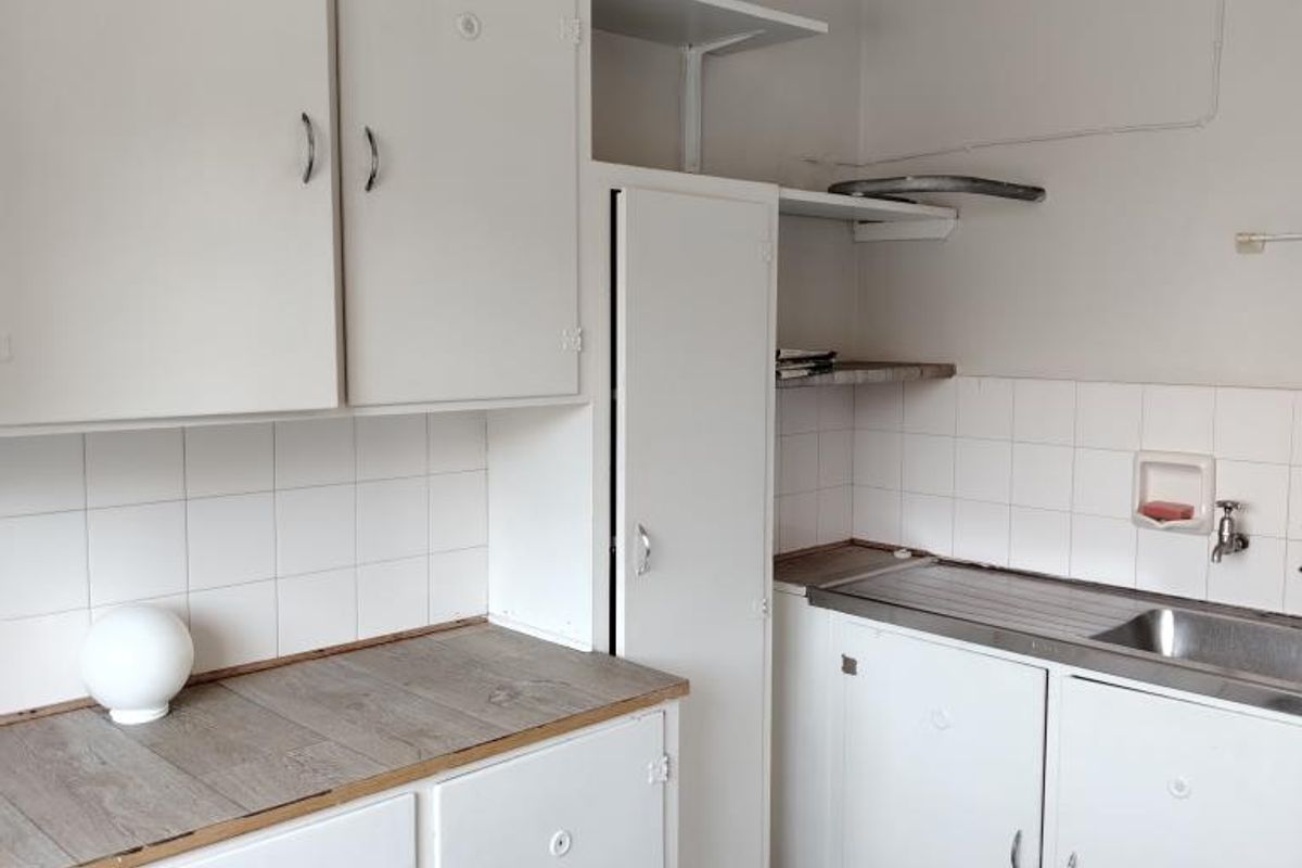 A functional kitchen area featuring white cabinetry, a stainless steel sink, and tiled splashbacks, offering a practical layout for renovation or modernization.