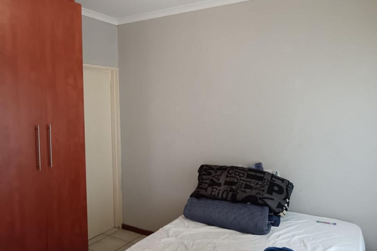 A bedroom featuring built-in wooden cabinetry and tiled flooring.