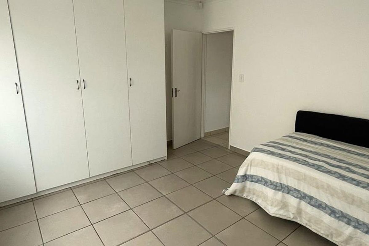 A bedroom featuring neutral tiled flooring and ample built-in cupboard storage space.