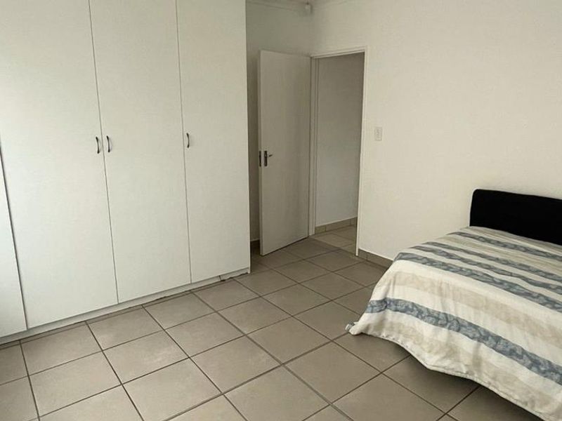 A bedroom featuring neutral tiled flooring and ample built-in cupboard storage space.