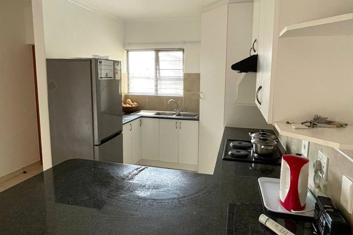 A functional kitchen featuring built-in cabinetry, dark granite countertops, a tiled backsplash, and a built-in hob with an extractor fan.