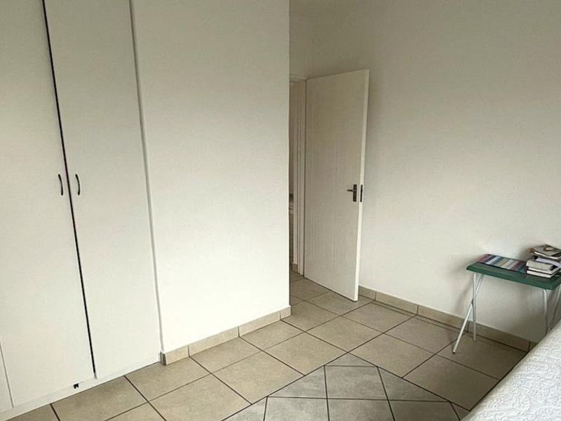 A bedroom featuring built-in cupboards and tiled flooring, providing a functional and neutral space.
