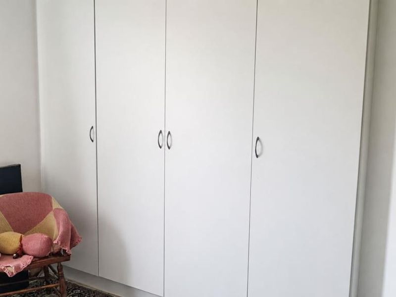 A bedroom featuring floor-to-ceiling built-in cupboards with white doors, providing ample storage space.