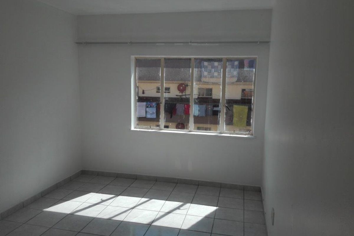 An empty bedroom featuring tiled flooring and a curtain rail, providing a blank canvas for personalization.